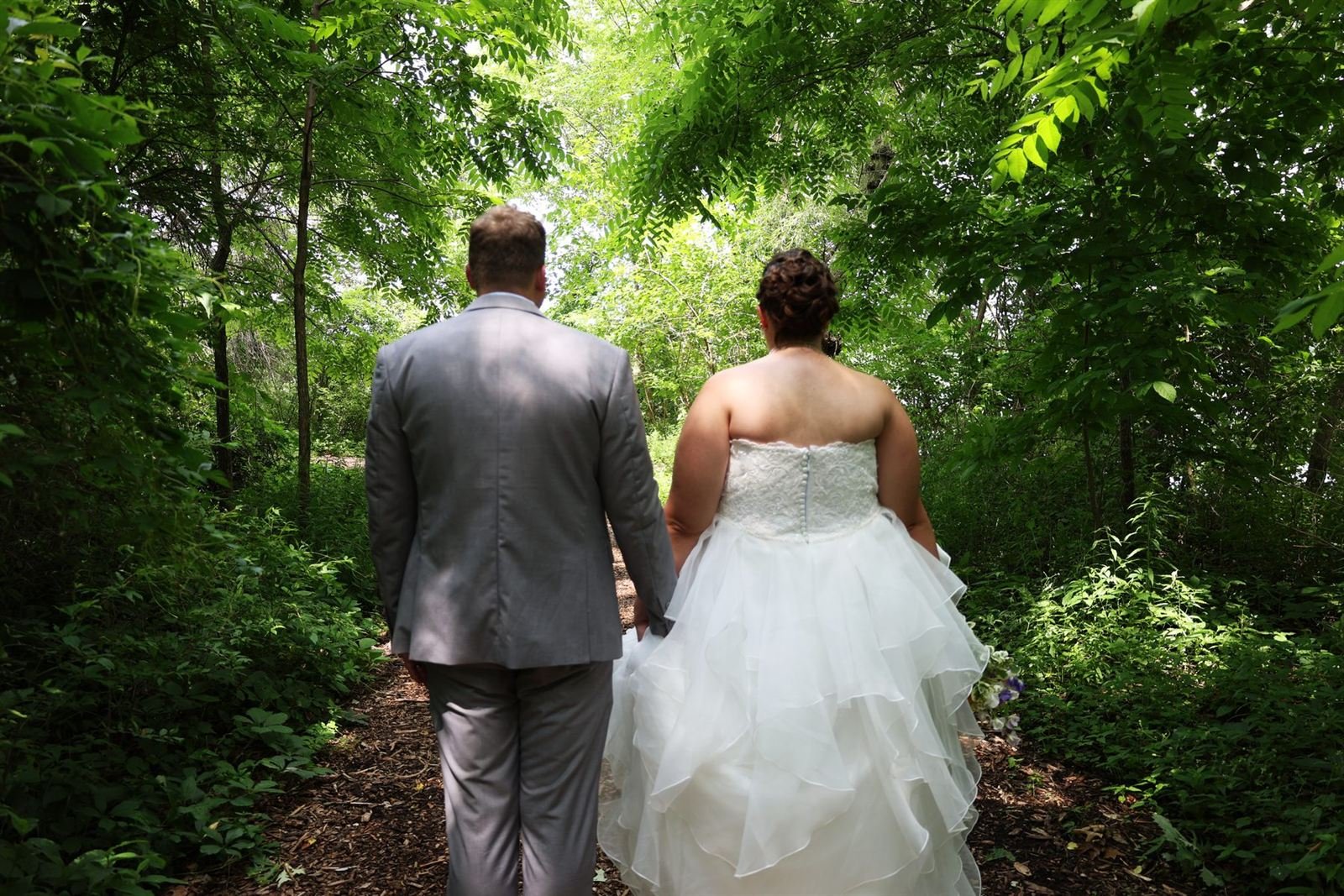 Into the green — bride and groom walking down a garden path