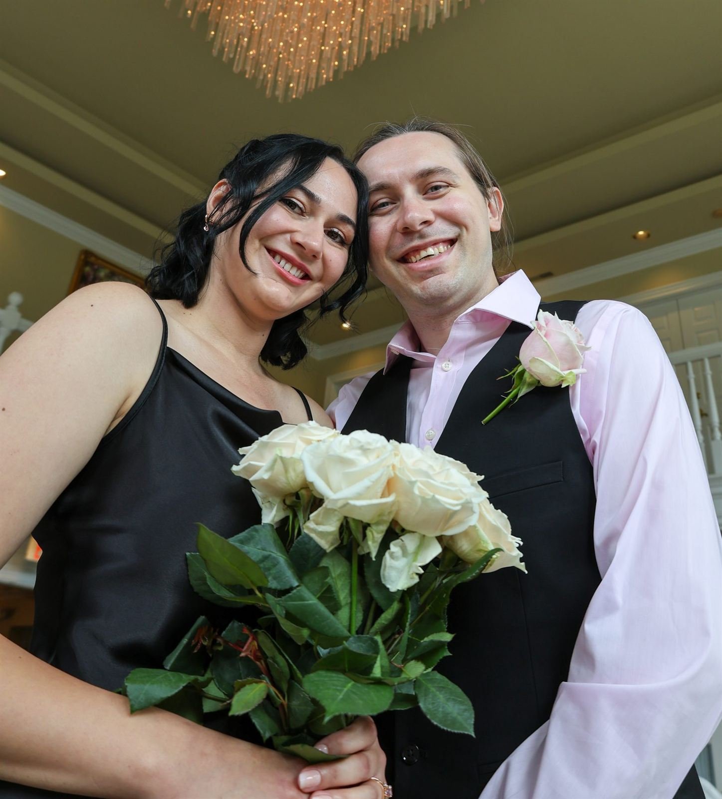 Just married — couple smiling with a bouquet of white roses