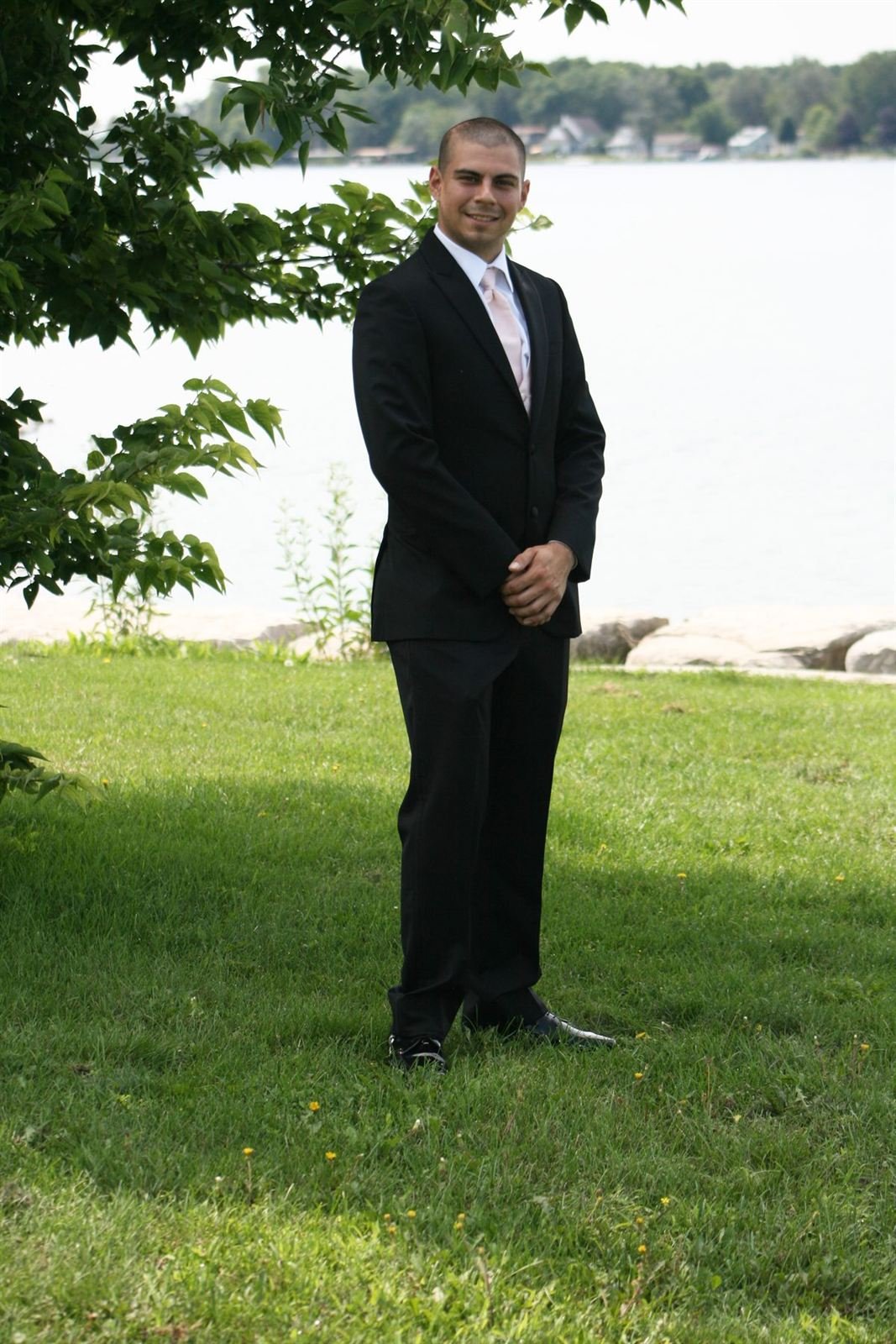 Shoreline — man in a suit on a lakeside lawn